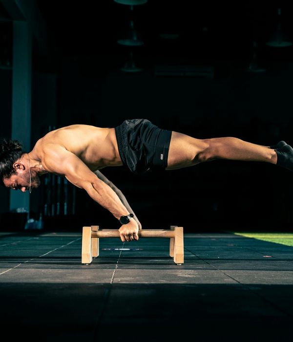 Man performing a controlled strength exercise in a dark modern gym.